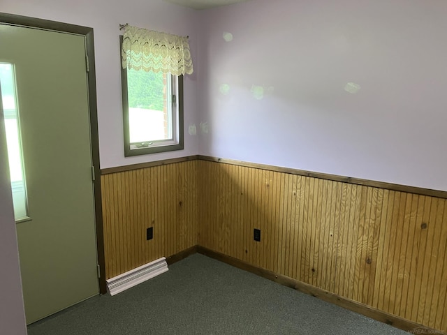 carpeted spare room featuring wooden walls