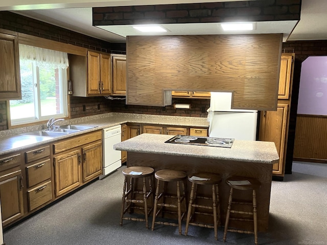 kitchen featuring a breakfast bar area, brick wall, sink, and white dishwasher