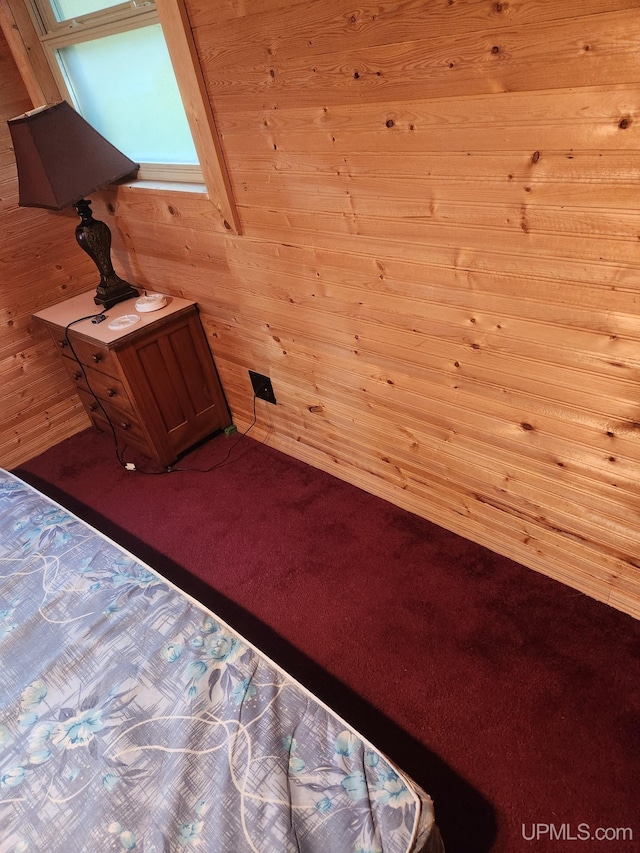 unfurnished bedroom featuring carpet flooring and wooden walls