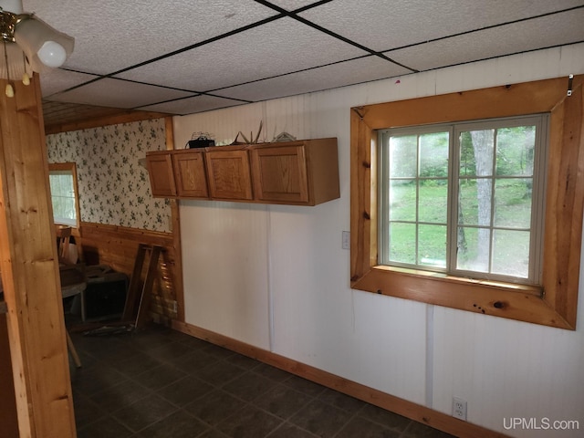 kitchen featuring a paneled ceiling and wood walls