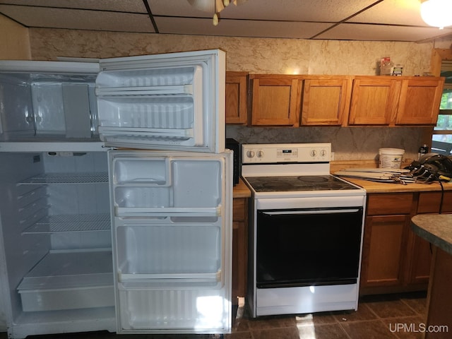 kitchen with white appliances, a paneled ceiling, and dark tile patterned floors