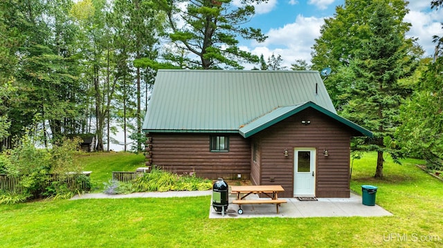 back of property with log siding, a yard, a patio area, and metal roof