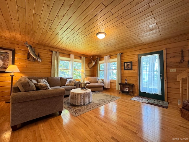 living room featuring light wood-type flooring, wooden ceiling, and wooden walls