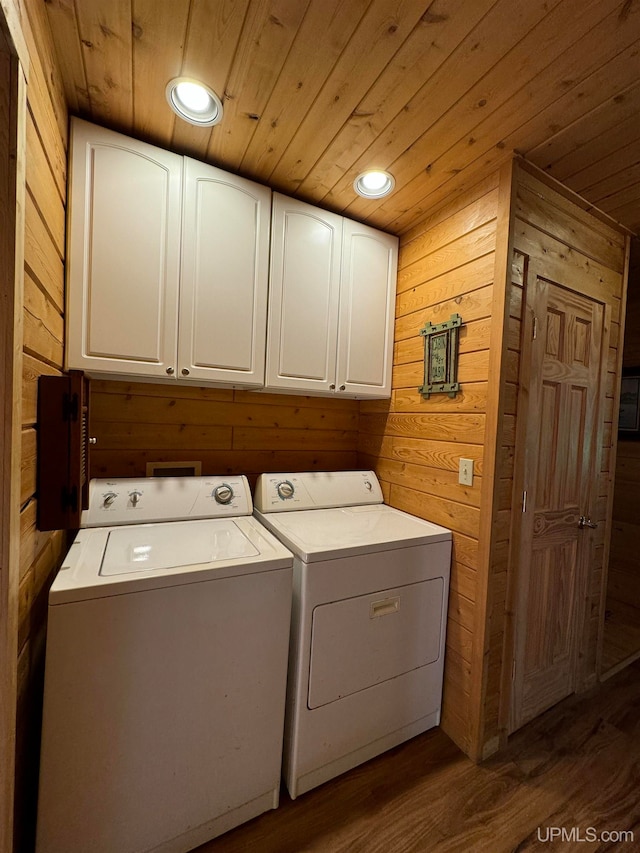 washroom with wooden ceiling, cabinets, wood-type flooring, washing machine and clothes dryer, and wooden walls