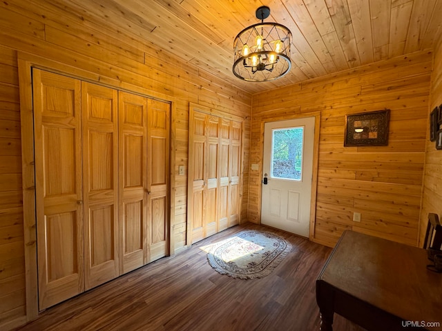 foyer featuring a notable chandelier, wood-type flooring, and wooden walls