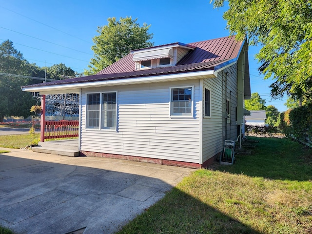 295 W Birch St, Harrison, MI 48625 - view of side of home featuring a lawn, a metal roof, and a patio