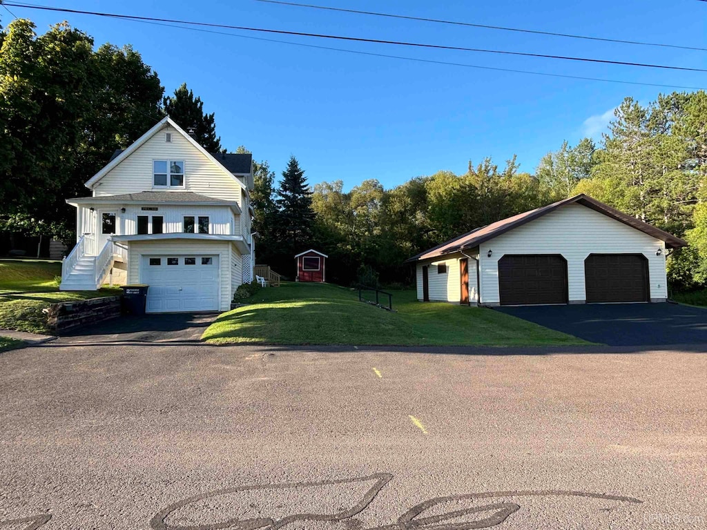 exterior space featuring a garage, a front lawn, and a shed