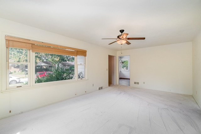 carpeted empty room with ceiling fan and a wealth of natural light