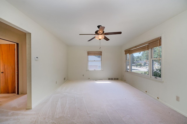 carpeted empty room featuring ceiling fan and plenty of natural light