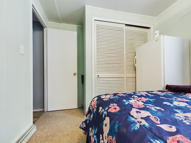 bedroom with a closet, light colored carpet, and a baseboard heating unit