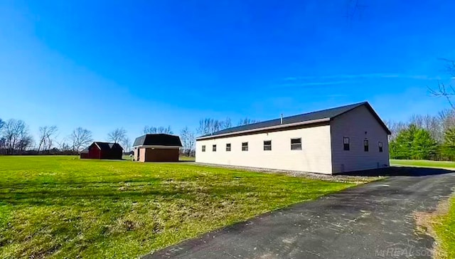 view of property exterior with an outdoor structure and a yard