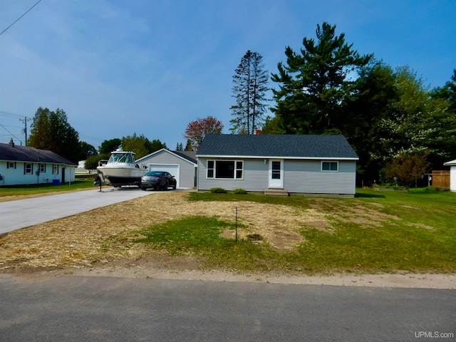 single story home featuring a garage, a front lawn, and an outbuilding