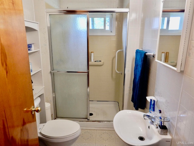 bathroom with a healthy amount of sunlight, a shower with shower door, tile walls, and toilet