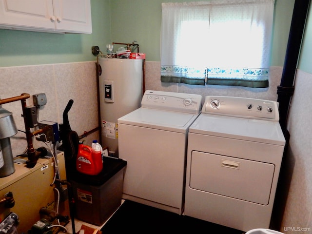 clothes washing area with cabinets, water heater, and washing machine and clothes dryer