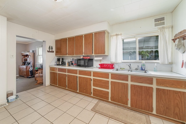 kitchen with light tile patterned flooring, crown molding, and sink