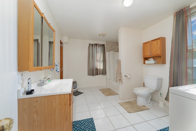 bathroom with washer / clothes dryer, a healthy amount of sunlight, toilet, and vanity