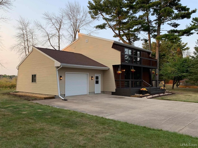 back house at dusk with a balcony, a garage, and a lawn