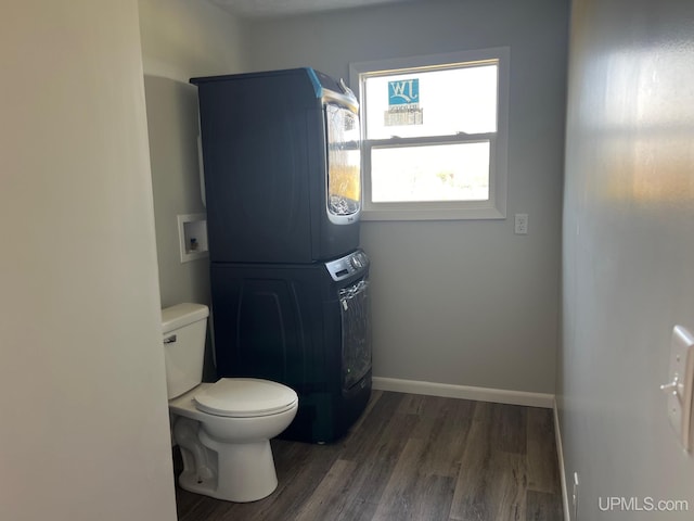 bathroom with stacked washing maching and dryer, toilet, and wood-type flooring