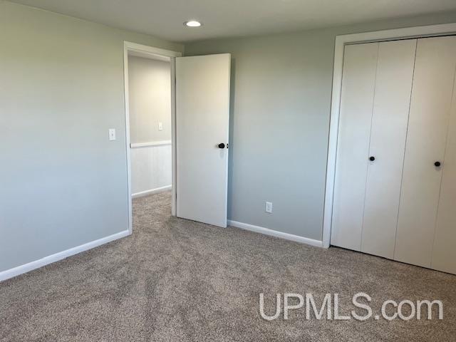 unfurnished bedroom featuring light colored carpet and a closet