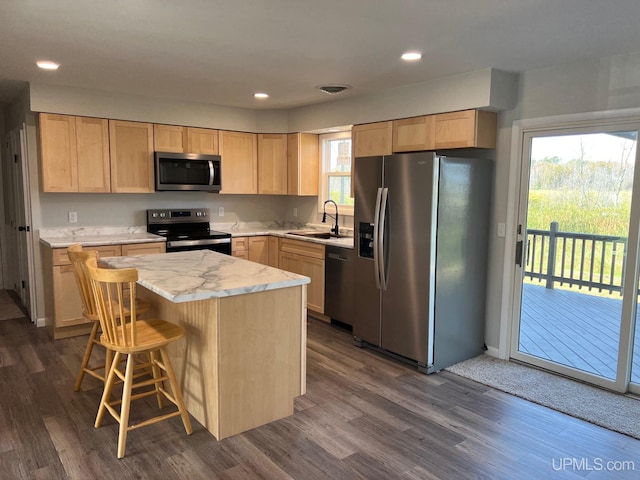 kitchen featuring light brown cabinetry, dark hardwood / wood-style flooring, a center island, and appliances with stainless steel finishes