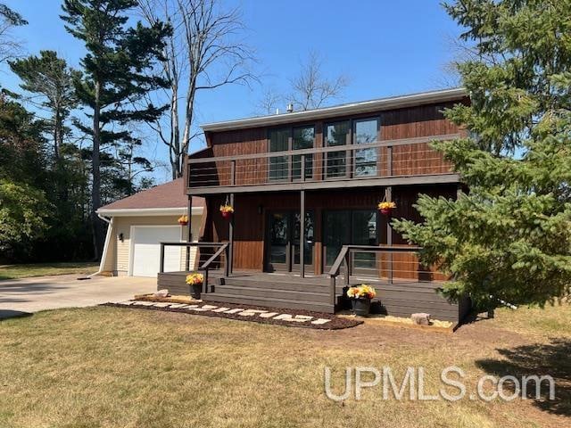 view of front facade with a balcony, a front yard, and a garage