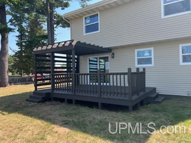 rear view of house with a wooden deck and a yard