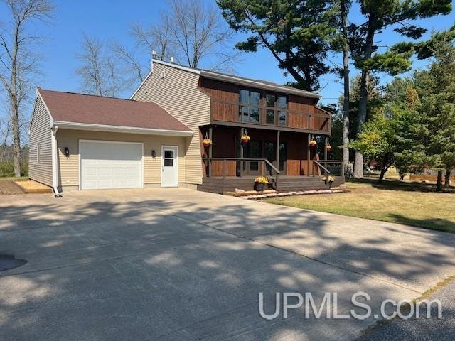 view of front of property featuring covered porch, a garage, and a front lawn