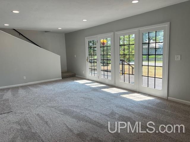 unfurnished living room featuring carpet flooring and french doors