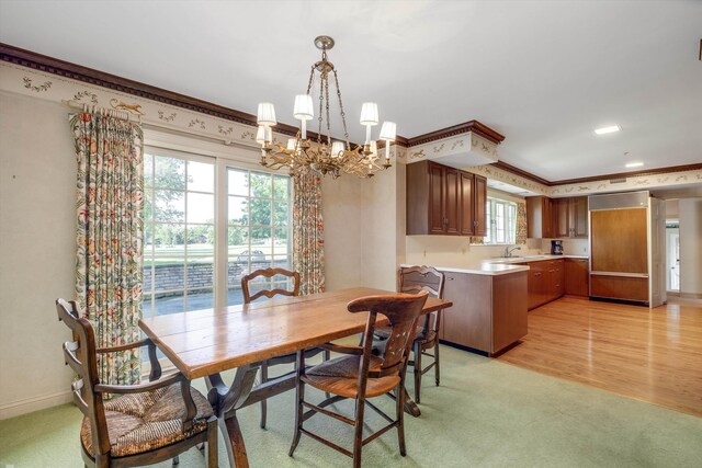 dining room with light wood-type flooring, crown molding, an inviting chandelier, and sink