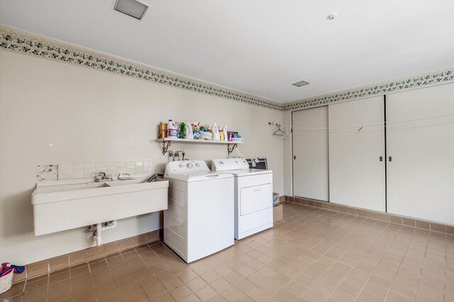 laundry room with light tile patterned flooring, washing machine and clothes dryer, and sink