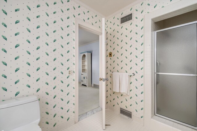 bathroom with toilet, a shower with door, and crown molding