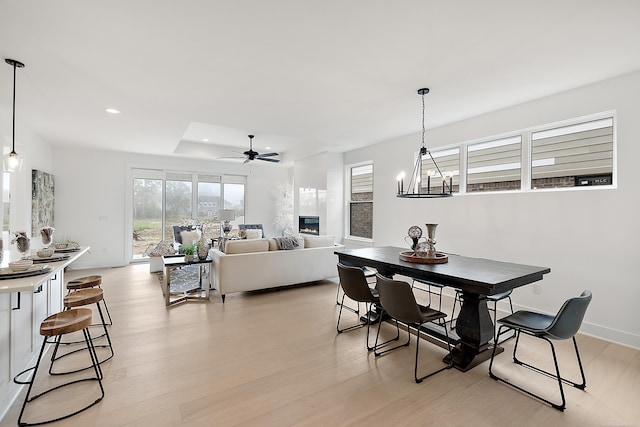 dining space with a fireplace, light hardwood / wood-style floors, and ceiling fan with notable chandelier