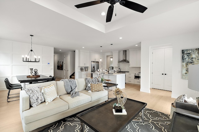 living room featuring ceiling fan with notable chandelier and light hardwood / wood-style floors