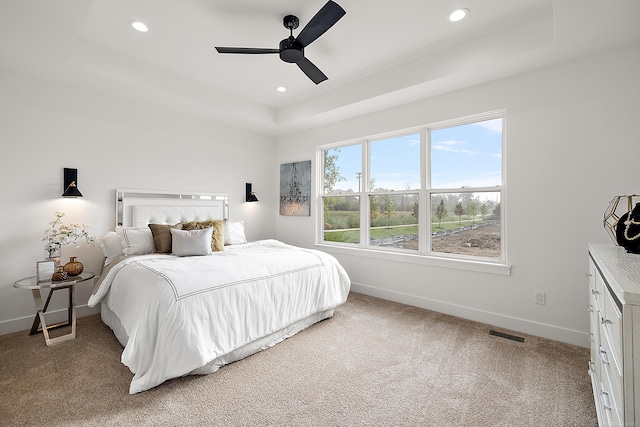 bedroom featuring a raised ceiling, ceiling fan, and carpet floors