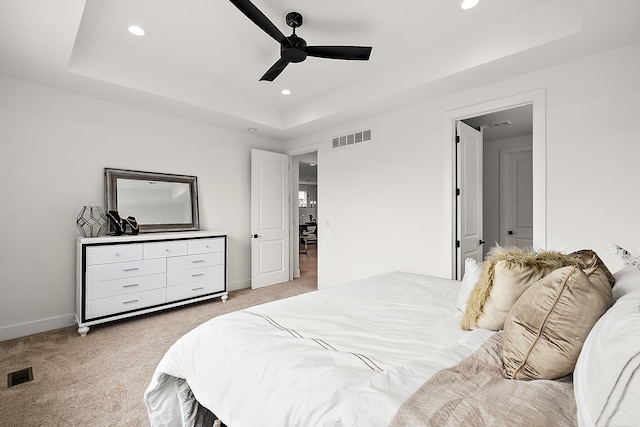 bedroom with light colored carpet, ceiling fan, and a raised ceiling