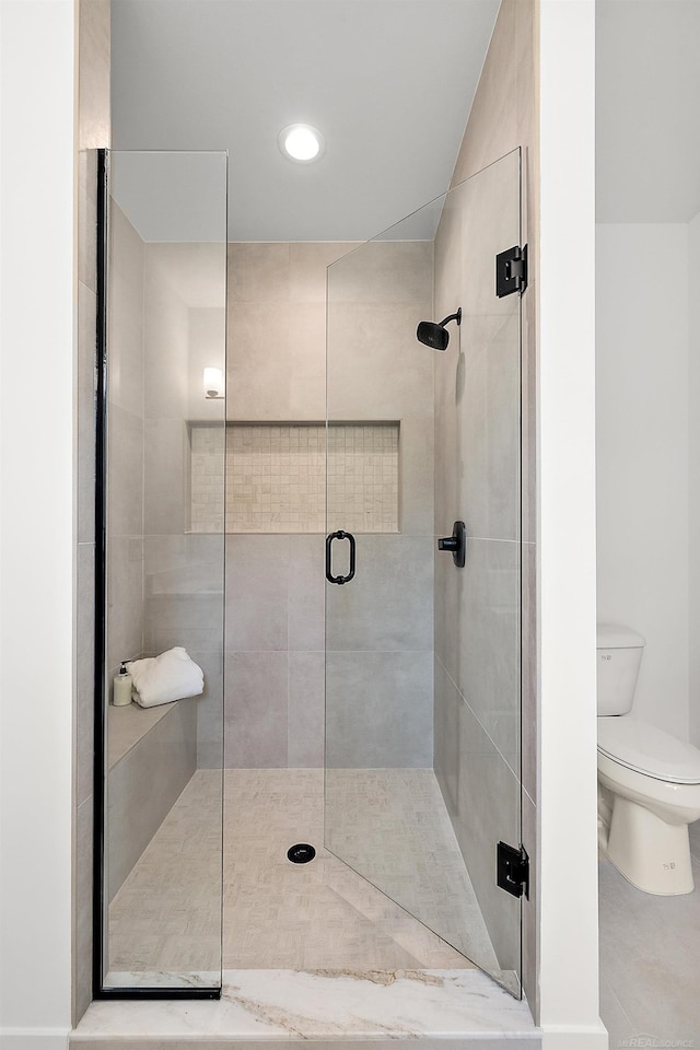 bathroom featuring a shower with shower door and toilet