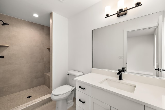 bathroom featuring toilet, vanity, and tiled shower