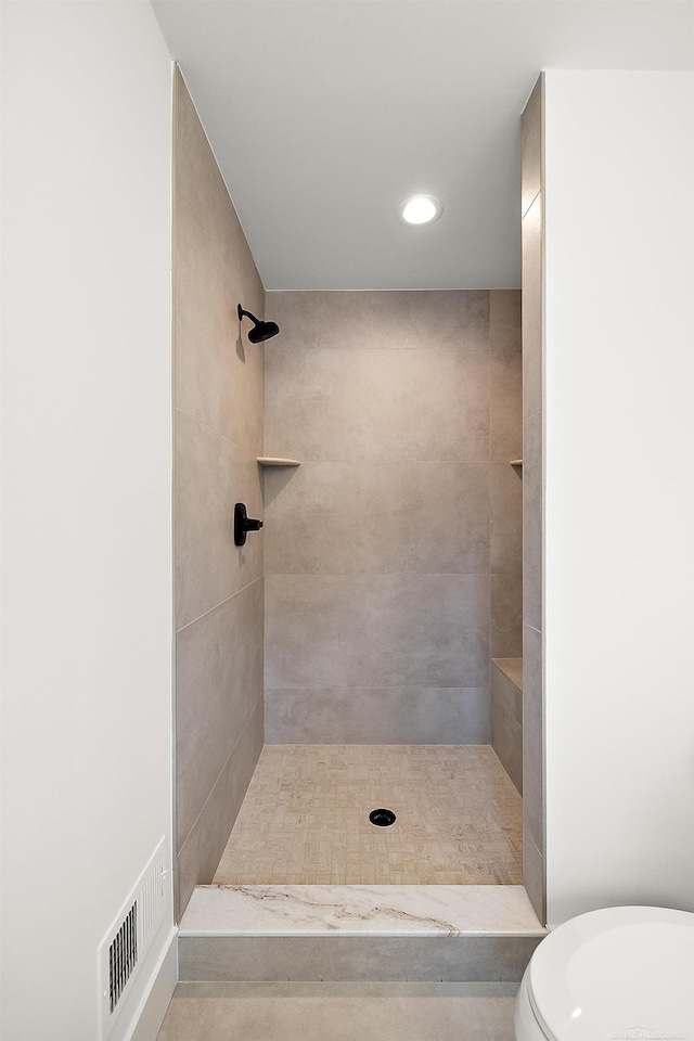 bathroom featuring toilet and a tile shower