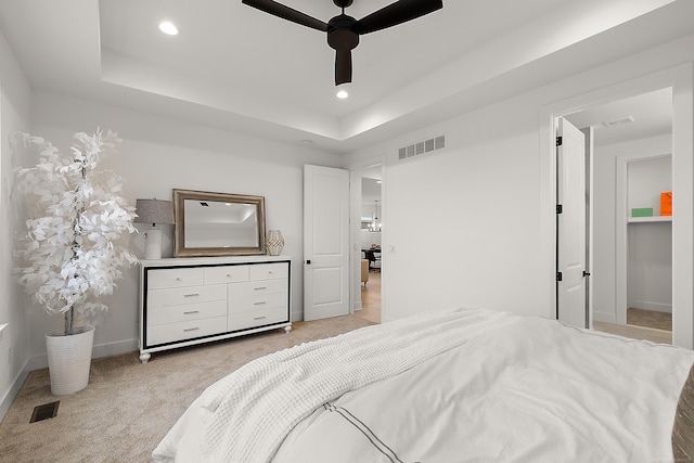 bedroom with a tray ceiling, light carpet, and ceiling fan