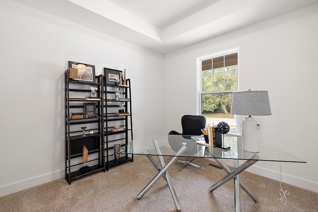 carpeted office featuring a raised ceiling