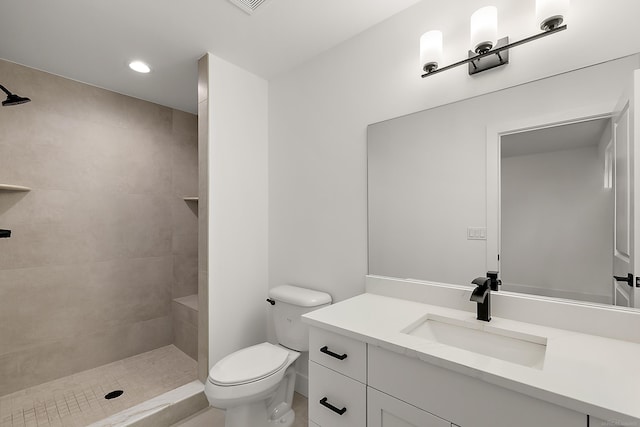 bathroom with tile patterned flooring, vanity, toilet, and tiled shower