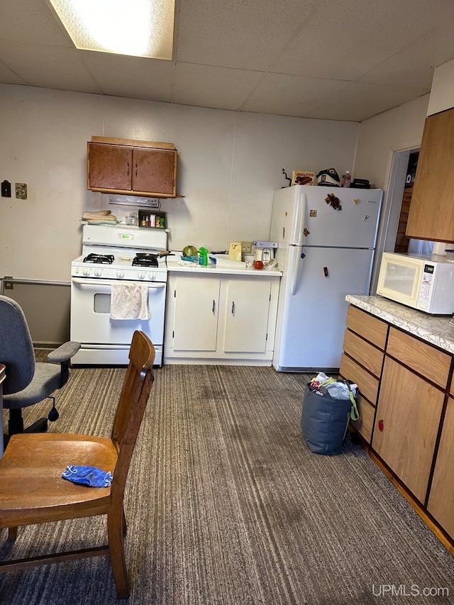 kitchen featuring white appliances, a paneled ceiling, and dark colored carpet