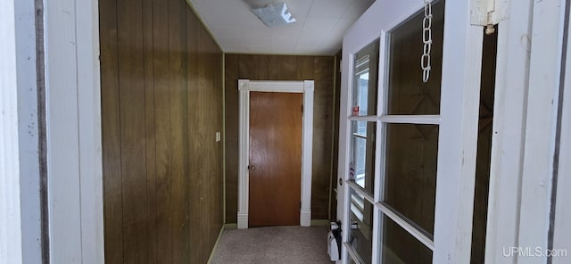 corridor featuring wooden walls and carpet