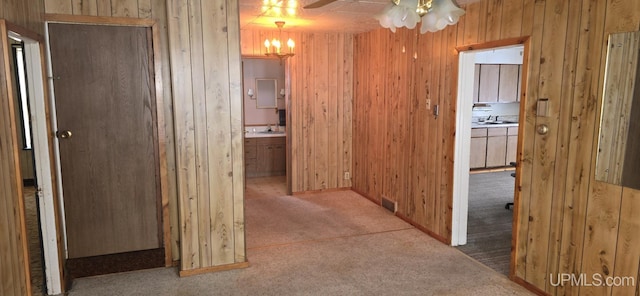 corridor with sink, wooden walls, and carpet