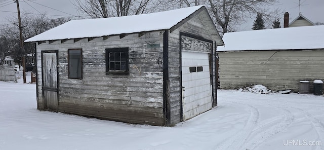 snow covered structure with a garage