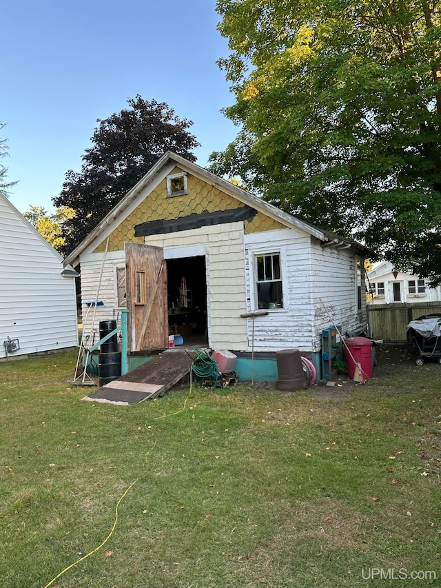 back of property featuring a yard and a storage unit