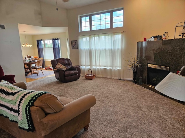 carpeted living room featuring plenty of natural light, a high ceiling, a chandelier, and a fireplace