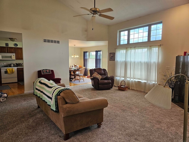 living room featuring a towering ceiling, ceiling fan with notable chandelier, and wood-type flooring