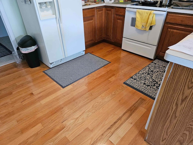 kitchen featuring white appliances and light hardwood / wood-style flooring