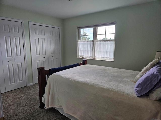 bedroom featuring two closets and dark colored carpet